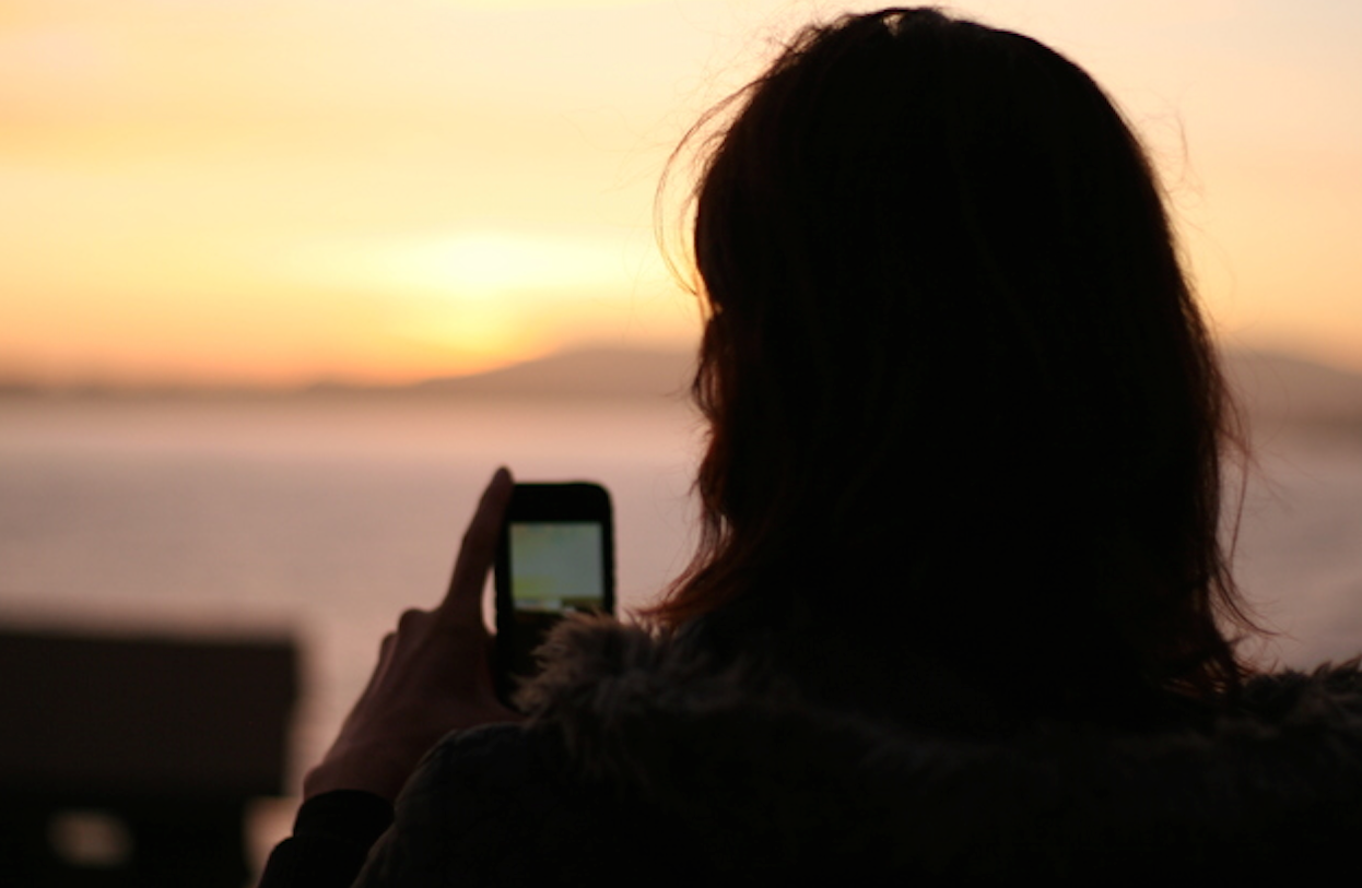 Girl with smartphone at sunset